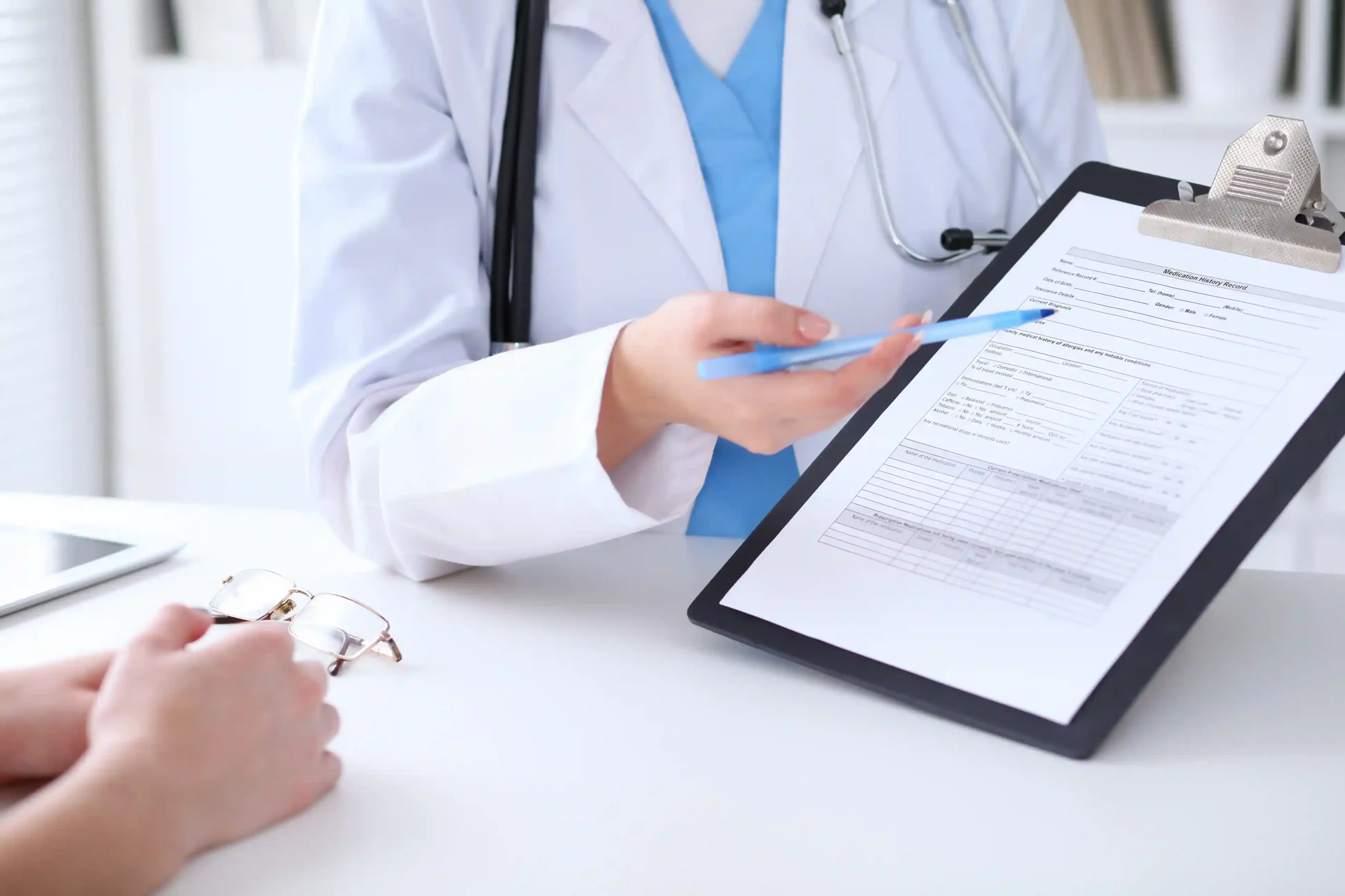 A physician points to a treatment plan on a clipboard during a podiatry appointment.