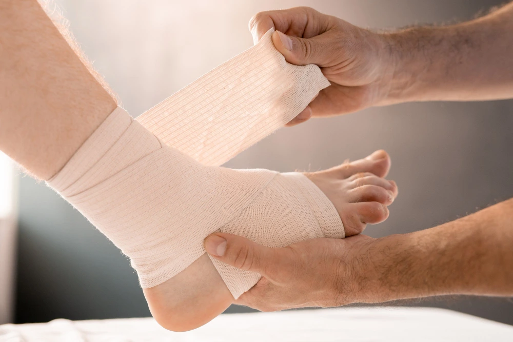 Doctor wrapping patient’s foot with elastic bandage for diabetic wound care