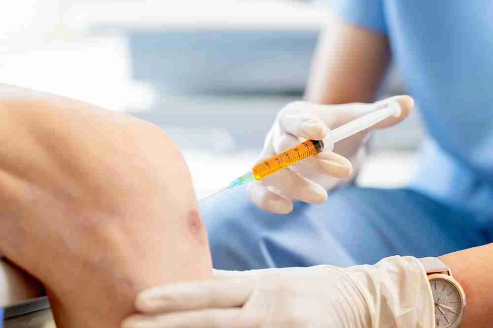Doctor administering Liposana injection near knee for regenerative foot treatment